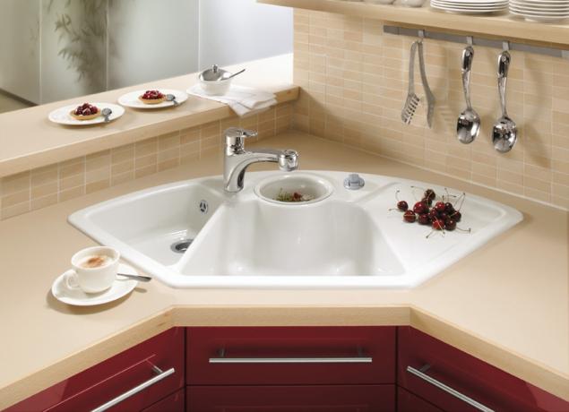 The photo shows a kitchen corner sink with three bowls and a drainer.