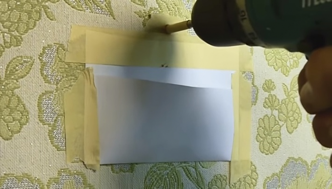Pocket made of paper and masking tape will protect wallpaper from dust that arises when drilling 